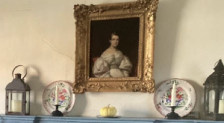 a framed portrait over a blue fireplace mantle along with two lanters and decorative plates